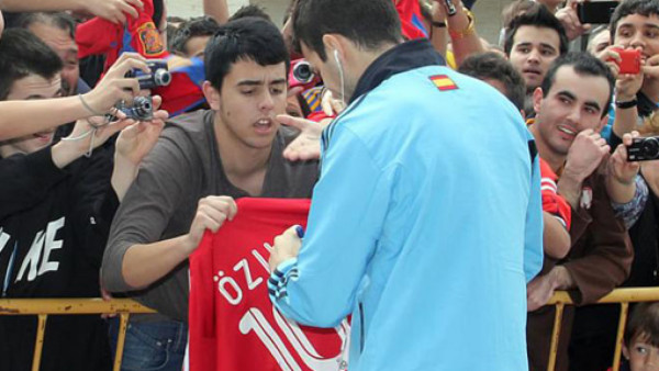 Cesc firma un autógrafo en una camiseta del Real Madrid