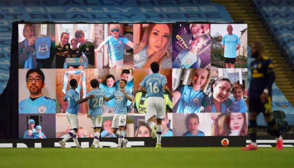 Manchester City's English midfielder Phil Foden (3L) celebrates scoring his team's third goal in front of a display showing pictures of the team's fans during the English Premier League football match between Manchester City and Arsenal at the Etihad Stadium in Manchester, north west England, on June 17, 2020. - The Premier League makes its eagerly anticipated return today after 100 days in lockdown but behind closed doors due to coronavirus restrictions. (Photo by Dave Thompson / POOL / AFP) / RESTRICTED TO EDITORIAL USE. No use with unauthorized audio, video, data, fixture lists, club/league logos or 'live' services. Online in-match use limited to 120 images. An additional 40 images may be used in extra time. No video emulation. Social media in-match use limited to 120 images. An additional 40 images may be used in extra time. No use in betting publications, games or single club/league/player publications. /