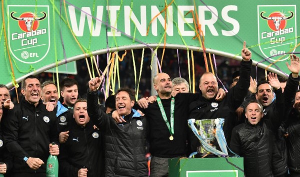 Manchester City's Spanish manager Pep Guardiola (C) celebrates with his backroom staff as City players celebrate their win after the English League Cup final football match between Aston Villa and Manchester City at Wembley stadium in London on March 1, 2020. - Manchester City won the game 2-1. (Photo by Glyn KIRK / AFP)