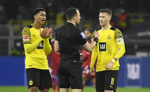 Dortmund's English midfielder Jude Bellingham (L) and Dortmund's German forward Marco Reus (R) discuss with referee Felix Zwayer after a deliberate handball during the German first division Bundesliga football match BVB Borussia Dortmund v FC Bayern Munich in Dortmund, western Germany, on December 3, 2021. (Photo by Ina FASSBENDER / AFP) / DFL REGULATIONS PROHIBIT ANY USE OF PHOTOGRAPHS AS IMAGE SEQUENCES AND/OR QUASI-VIDEO