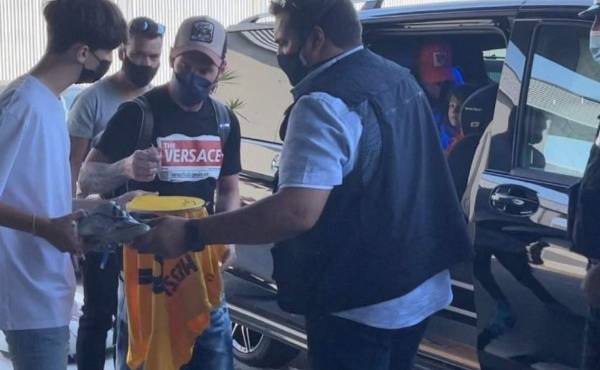Lionel Messi tras su llegada al aeropuerto firmando una camisa del Barcelona a un fans.