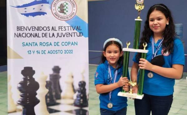 Ximena Bobadilla y Diana Bobadilla levantando el trofeo obtenido por su equipo en el torneo.