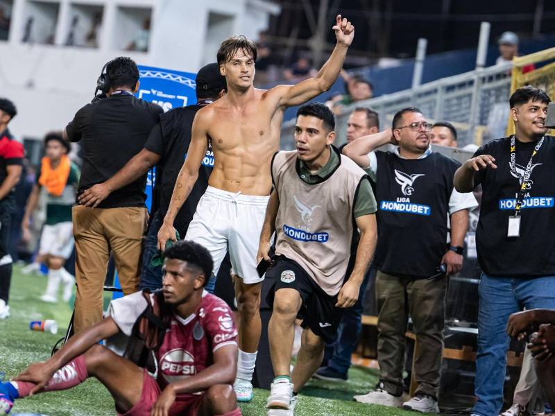 El mediocampista de Marathón, Bruno Farioli festeja ante la desilución de Jorge Serrano, volante del Motagua.