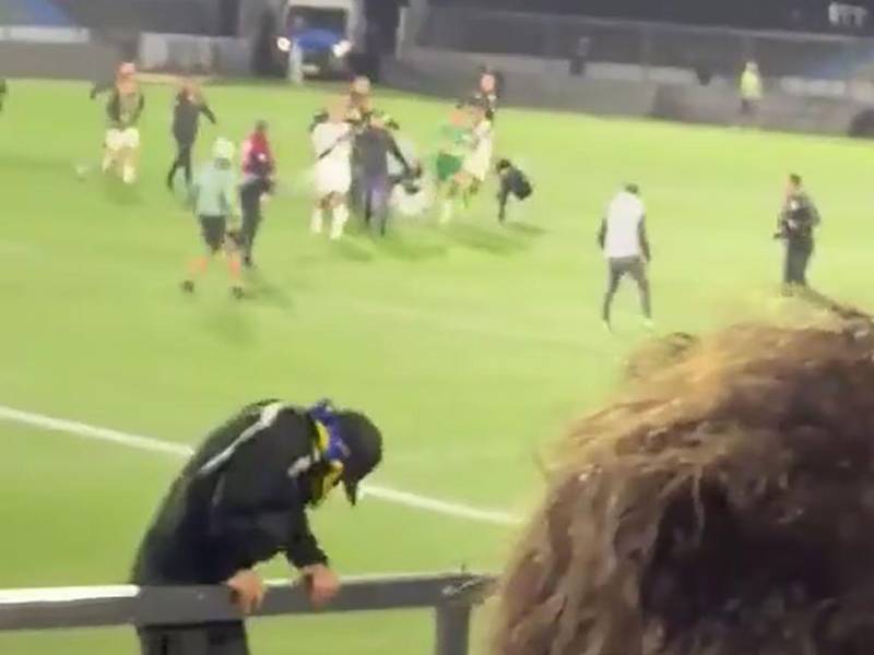 Aficionados del club Danubio ingresan al campo para confrontar a los futbolistas.